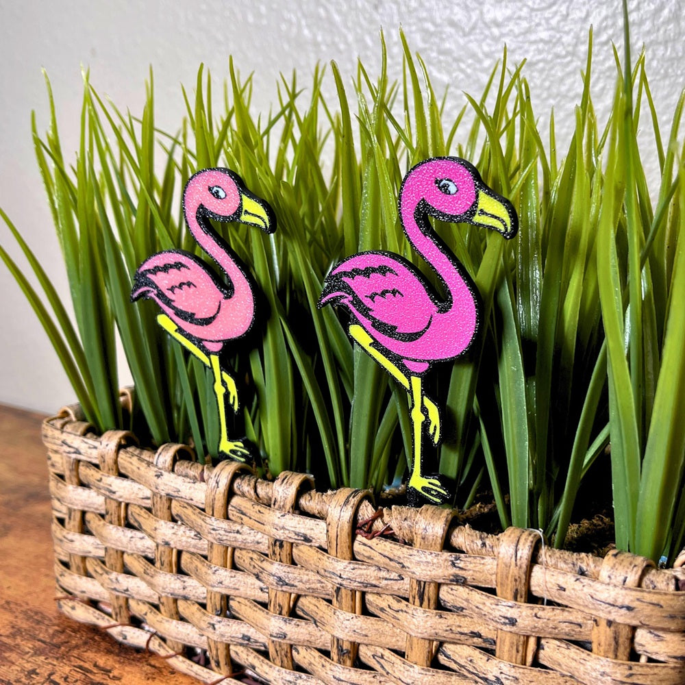 Fun flamingo plant stakes shown in a houseplant from an angle