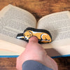 Adorable sleeping gold and white fur golden retriever dog book page holder shown holding a book open from the front view