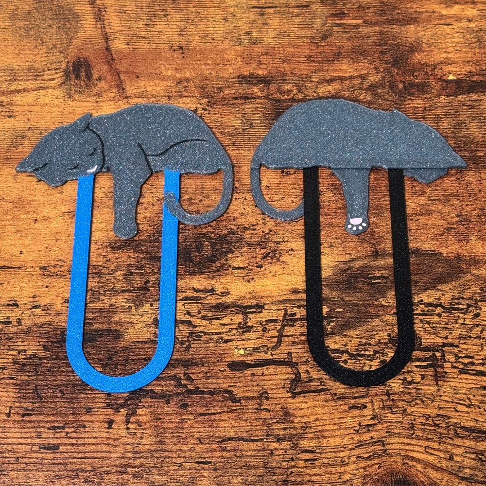 The front and back of a pair of grey cat bookmark showing the adorable pink toe beans on the back of its paw