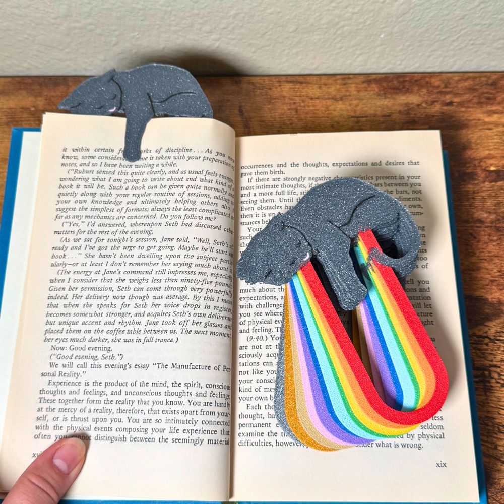 Adorable gray cat-themed bookmarks in twelve color variations laying on a book