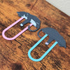 Close up angled shot of the pink and blue cat bookmarks showing the front and back of the design