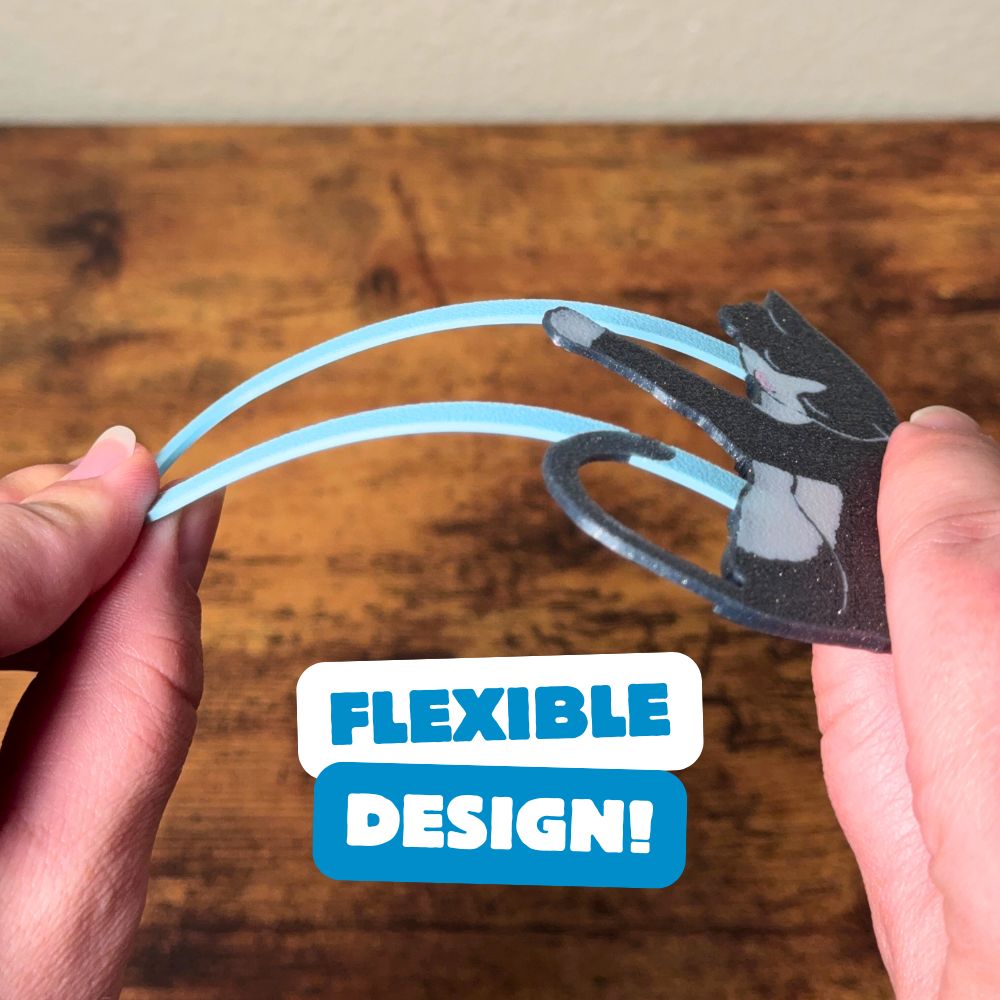 Gray tuxedo cat bookmark being bent, showing off its flexible design
