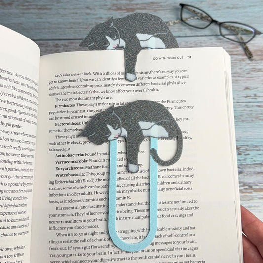 Gray and white tuxedo cat bookmarks shown in a book
