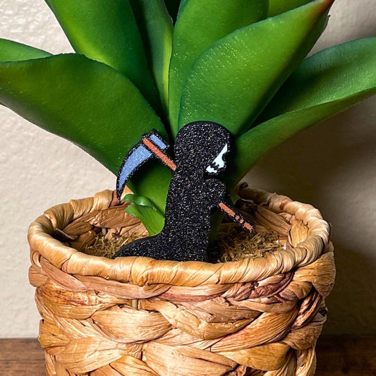 Cute grim reaper plant stake in a houseplant with a black robe