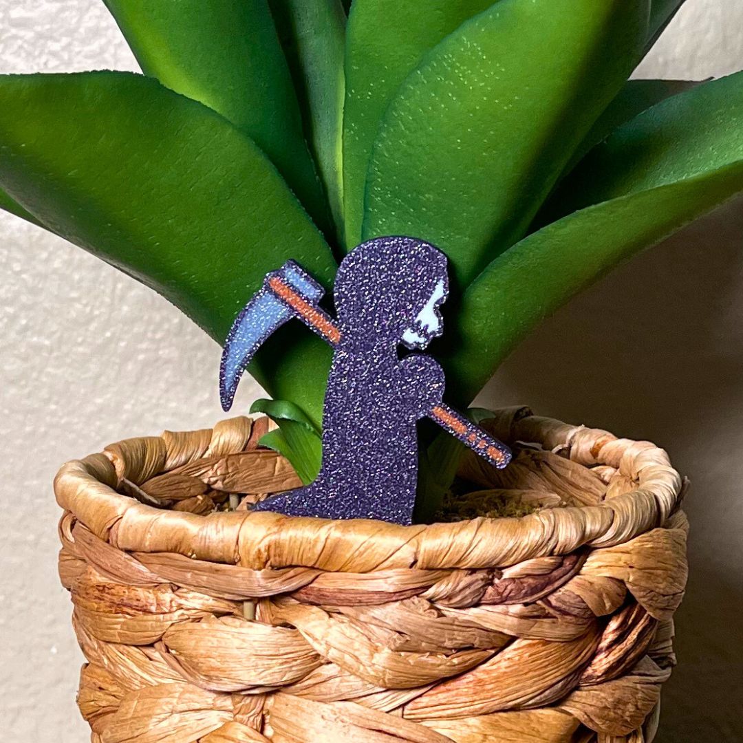 Cute grim reaper plant stake in a houseplant with a purple sparkling robe