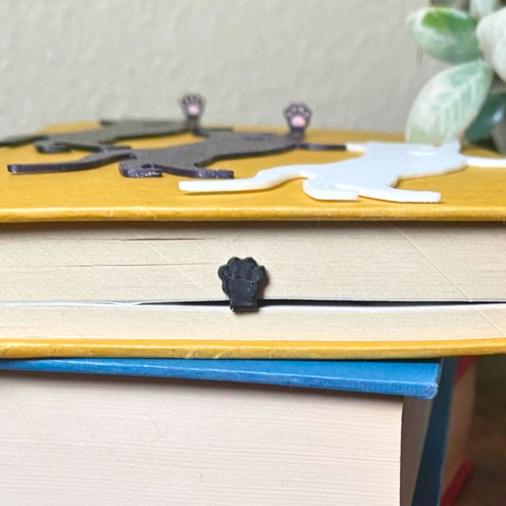 Fun cat bookmarks with a hanging paw and pink toe beans. The paw is shown from the top book view.