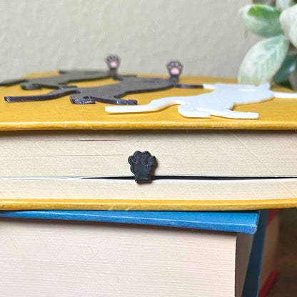 Fun cat bookmarks with a hanging paw and pink toe beans. The paw is shown from the top book view.