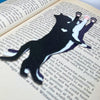 Fun cat bookmarks with a hanging paw and pink toe beans. Bookmarks shown in purple and black sparkle, as well as white