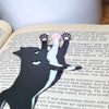 Fun cat bookmarks with a hanging paw and pink toe beans. Bookmarks shown in purple and black sparkle, as well as white