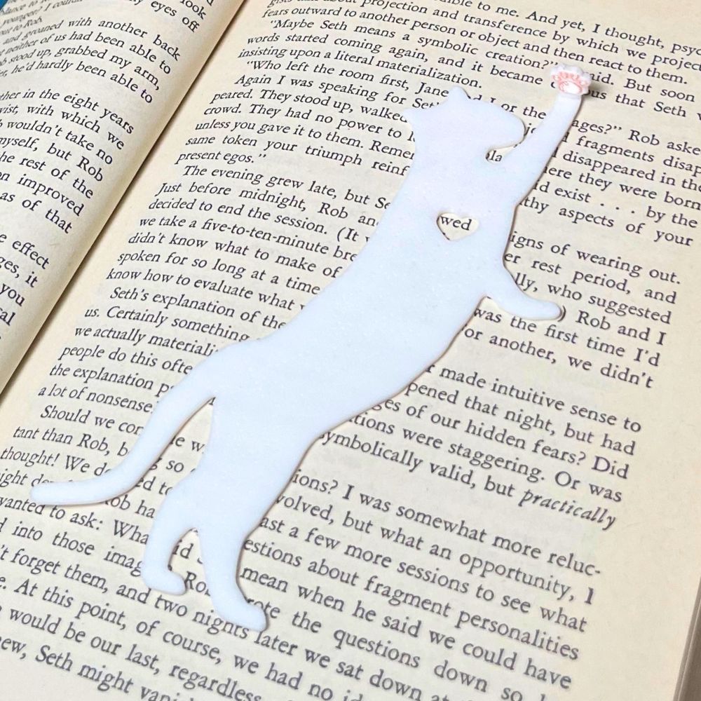 Fun cat bookmark with a hanging paw and pink toe beans. Bookmark shown in  
 white.