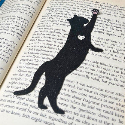 Fun cat bookmark with a hanging paw and pink toe beans. Bookmark shown in  black sparkle.