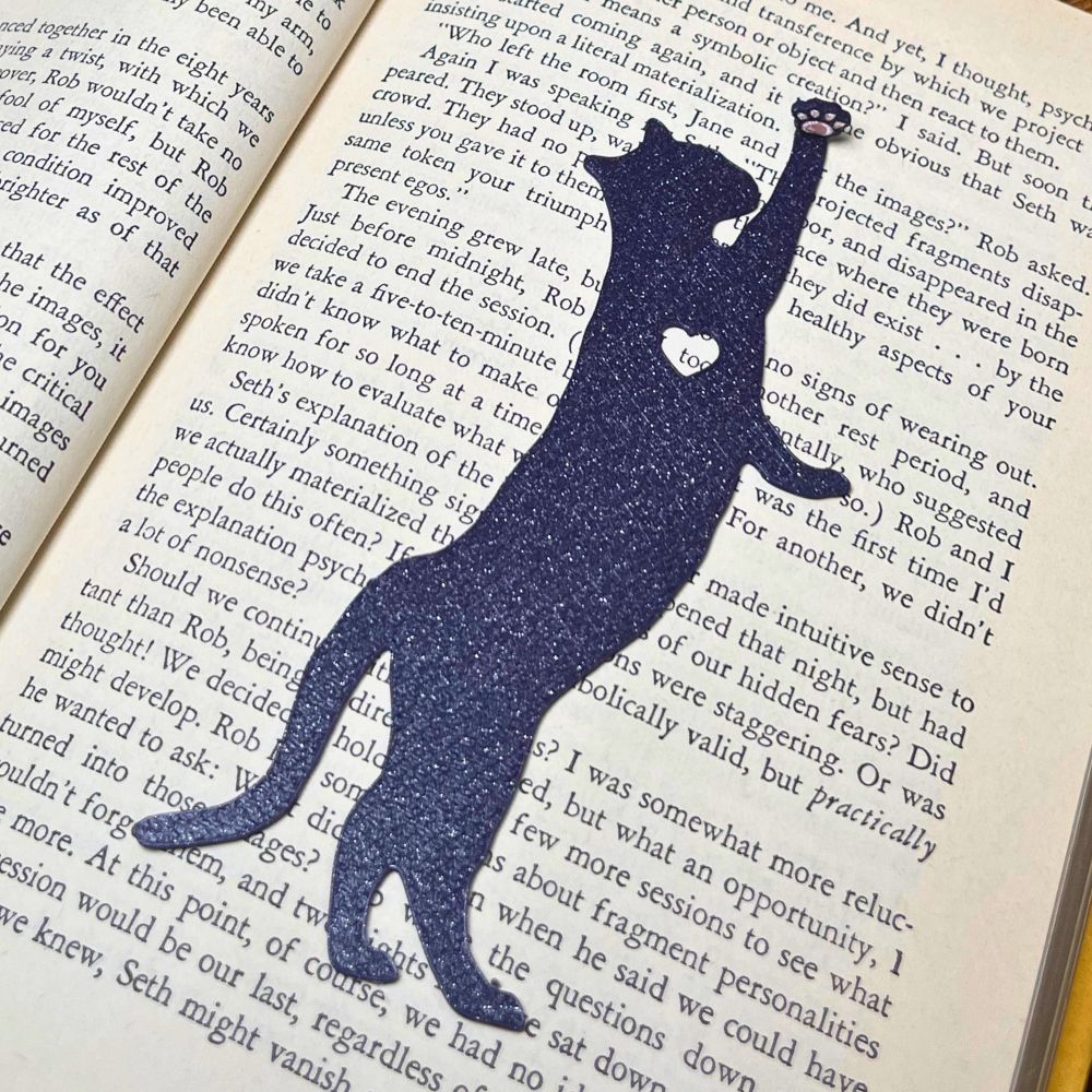 Fun cat bookmark with a hanging paw and pink toe beans. Bookmark shown in  purple sparkle.