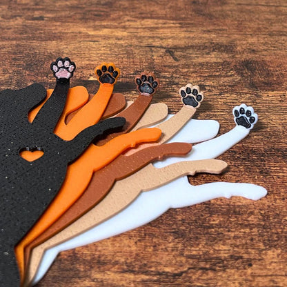 Five dog bookmarks in orange, white, tan, brown, and black sparkle laying down, showing their adorable paw toe beans close up