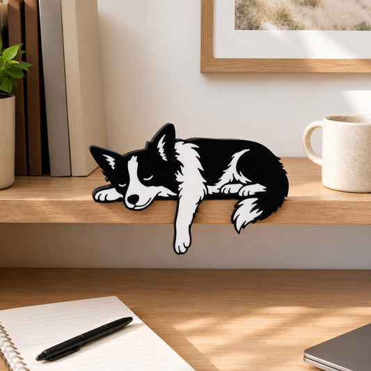 Sleeping Border Collie shelf pet draped over a light wood shelf edge beside books, a plant, and a speckled mug