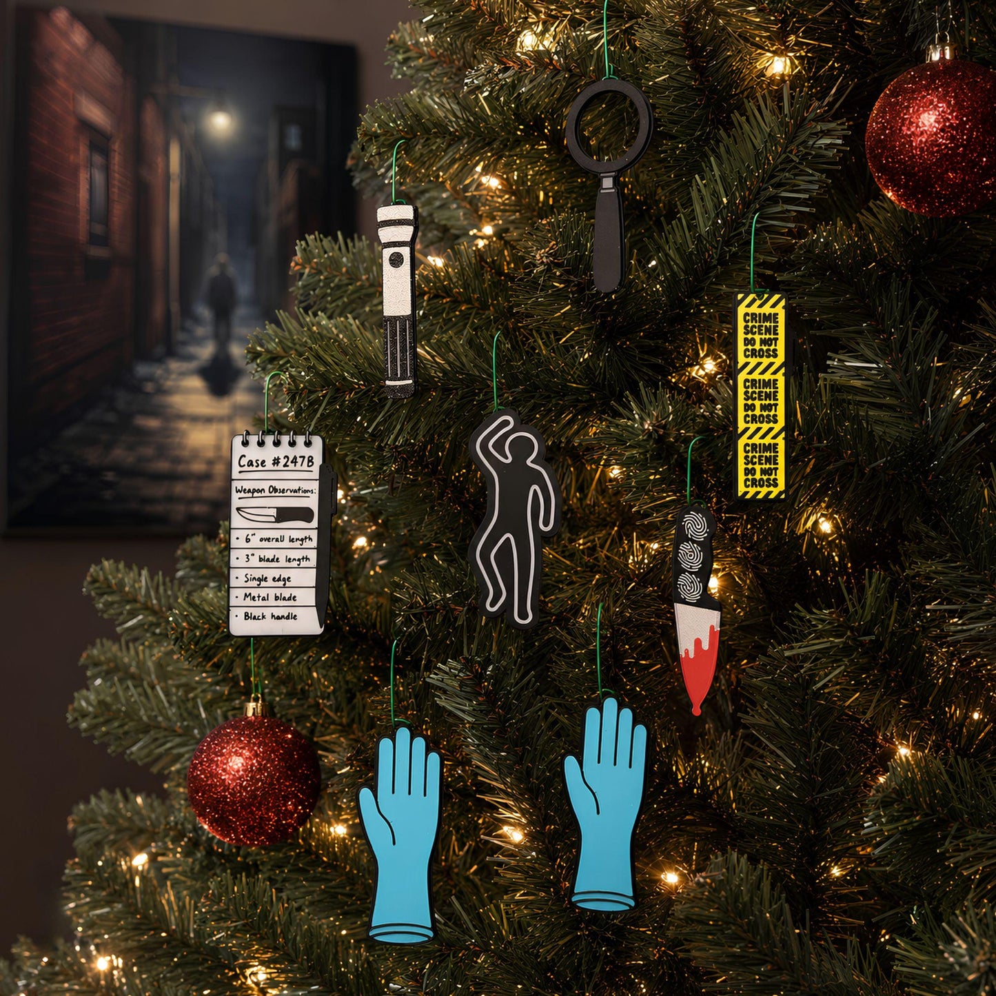 True crime ornaments hanging on a lit Christmas tree with red glitter baubles
