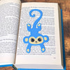 Fun blue monkey bookmark inside of a book