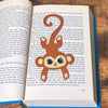 Cute brown monkey bookmark inside of a book