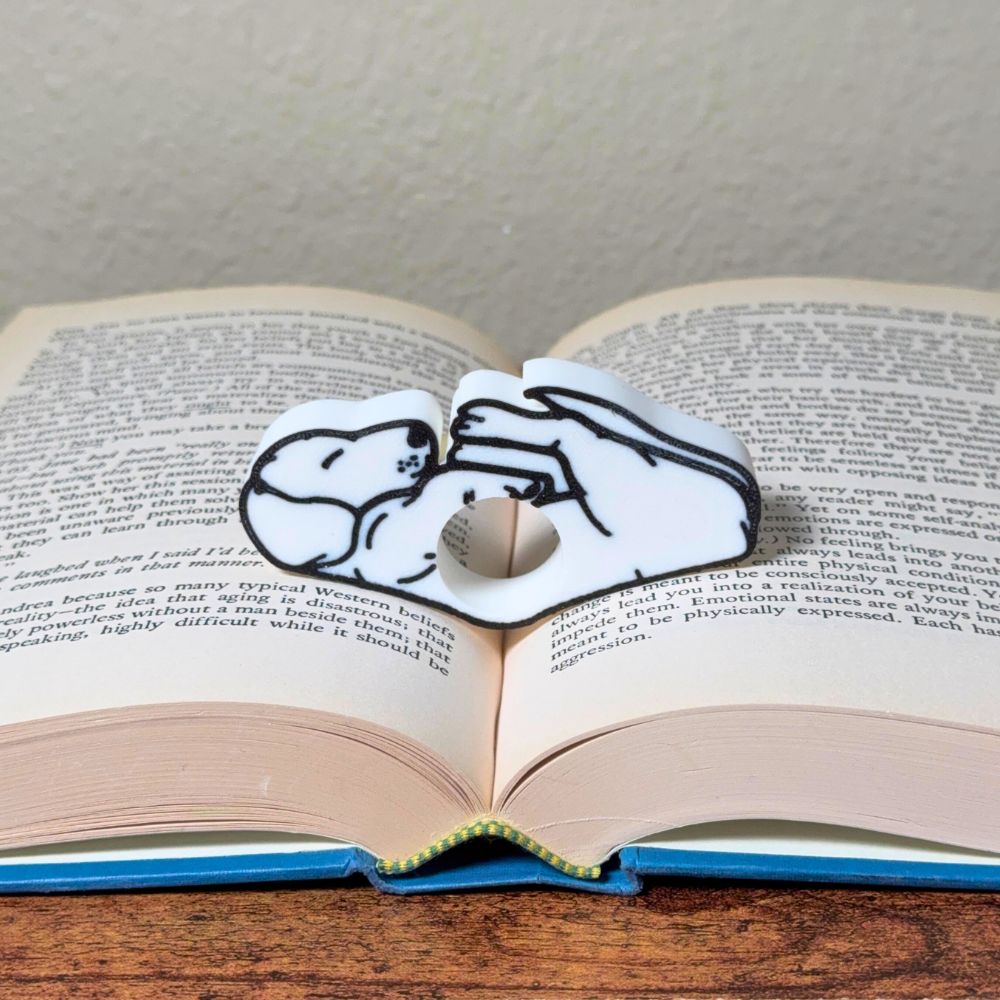Adorable sleeping white dog book page holder shown in a book