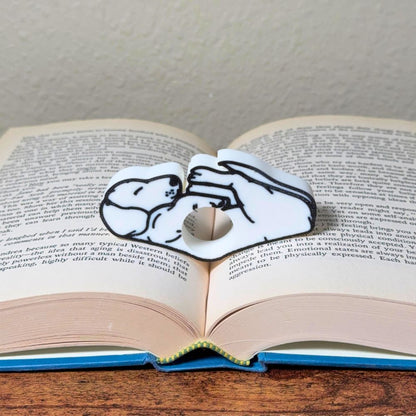 Adorable sleeping white dog book page holder shown in a book