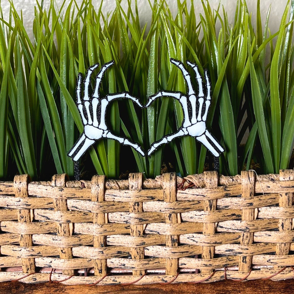 Skeleton bone hands in a heart shape inside of a houseplant