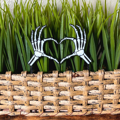 Skeleton bone hands in a heart shape inside of a houseplant