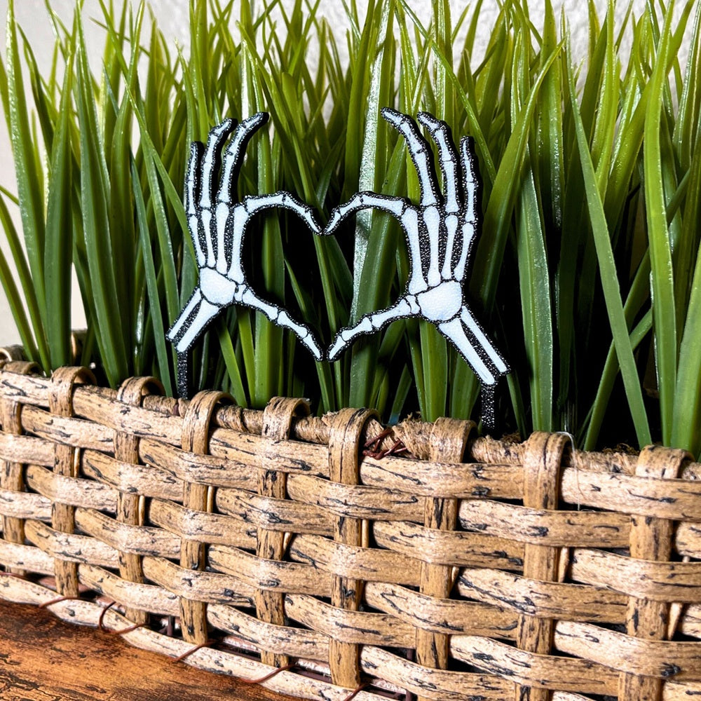Skeleton bone hands in a heart shape inside of a houseplant