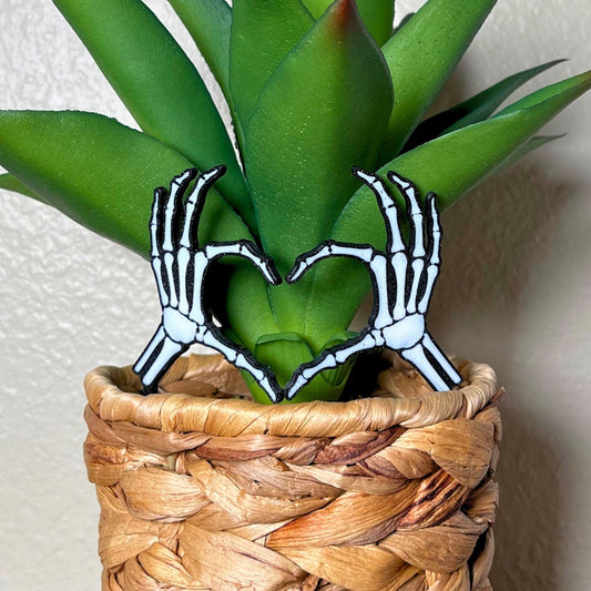 Skeleton bone hands in a heart shape inside of a houseplant