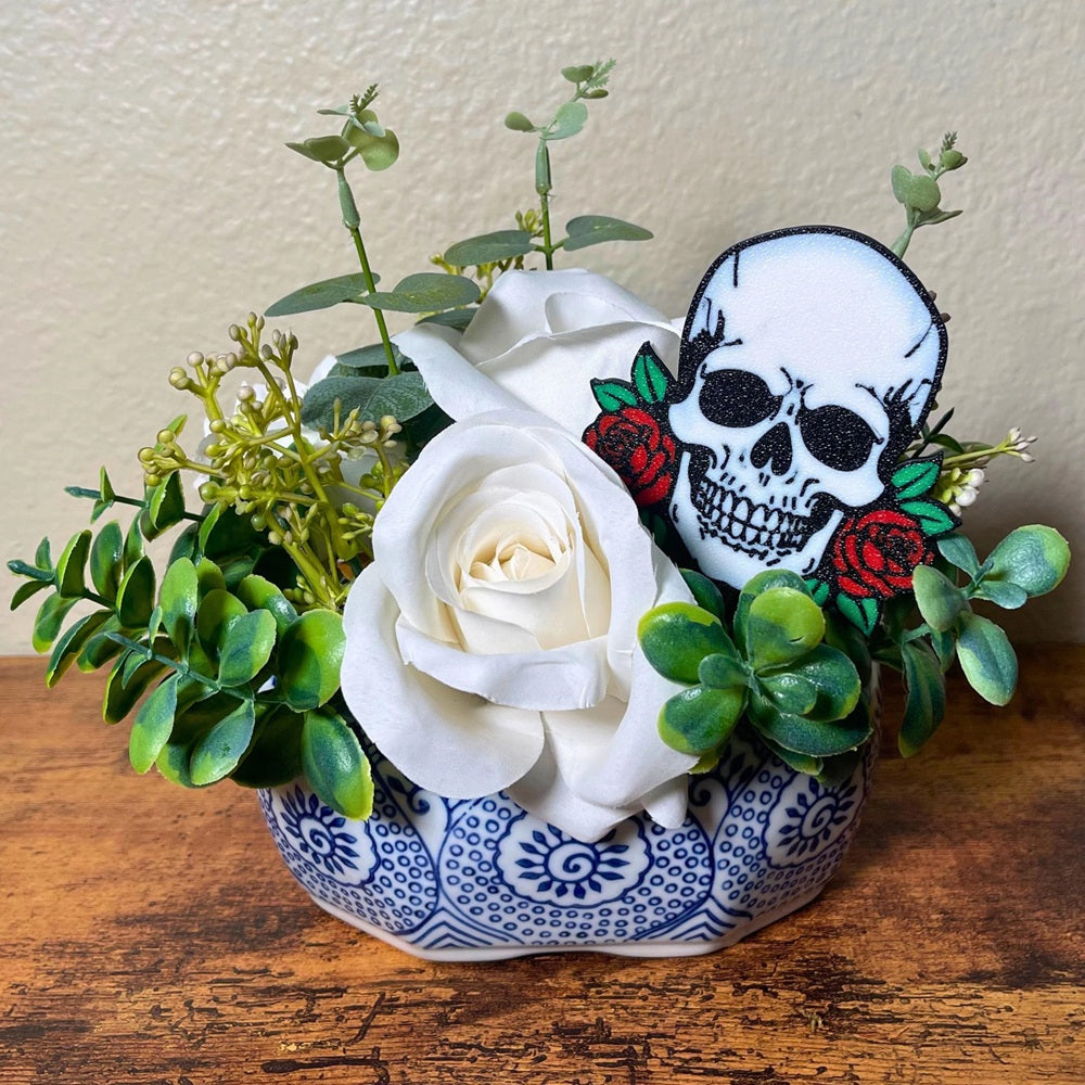 Gothic skull head with red roses on each side shown in a rose houseplant
