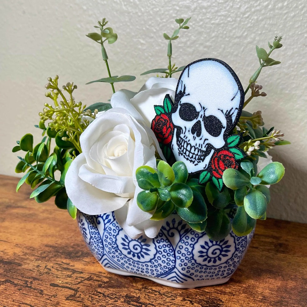 Gothic skull head with red roses on each side shown in a rose houseplant