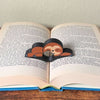 Adorable sleeping sloth book page holder shown holding a book open