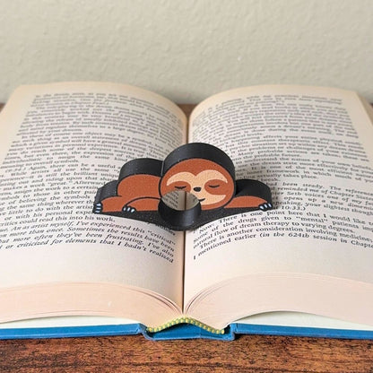 Adorable sleeping sloth book page holder shown holding a book open