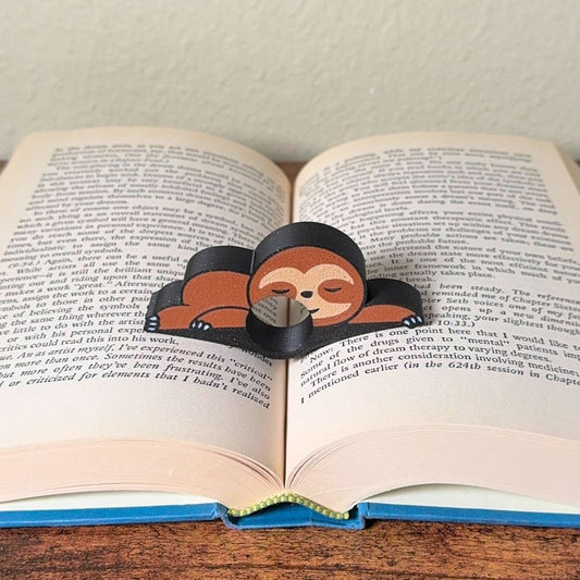 Adorable sleeping sloth book page holder shown holding a book open
