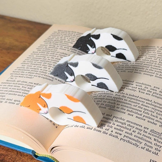 Adorable sleeping spotted cat book page holders shown in a book in orange gray and black