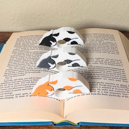 Adorable sleeping spotted cat book page holders shown in a book in orange gray and black from the front