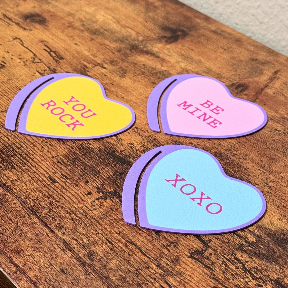 Sweet set of three bookmark hearts in pink, blue and yellow on top of a wooden surface shown from an angle