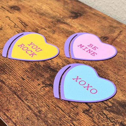 Sweet set of three bookmark hearts in pink, blue and yellow on top of a wooden surface shown from an angle