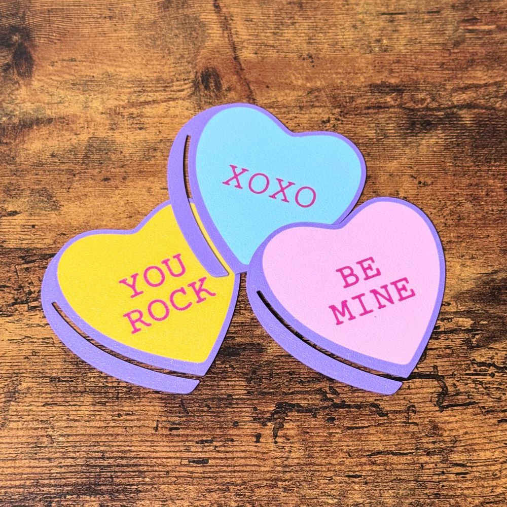 Sweet set of three bookmark hearts in pink, blue and yellow on top of a wooden surface