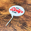 The punny Talk Dirty to Me plant stake on a wooden surface