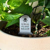 Tombstone that reads "Serial Plant Killer" in the dirt of a houseplant close up