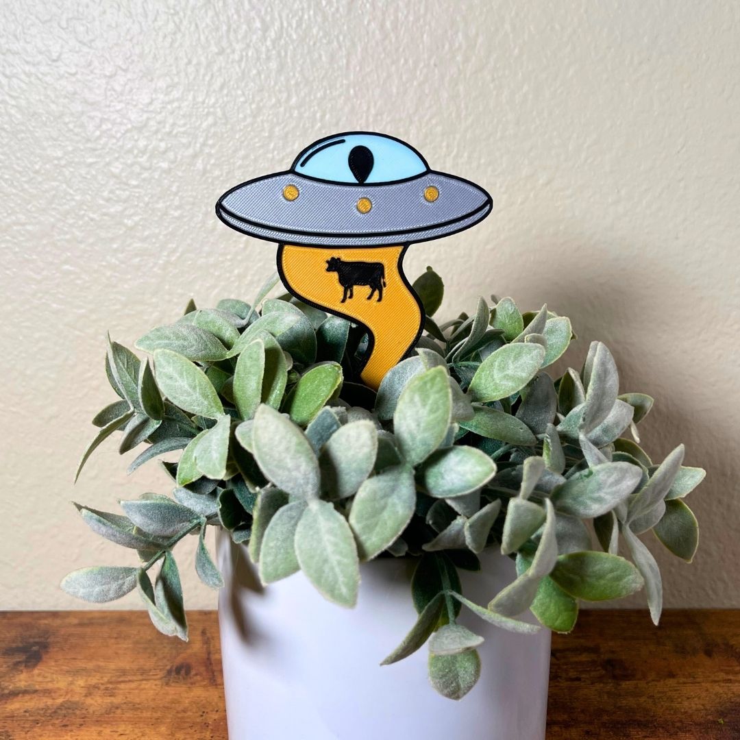 UFO Plant stake with alien inside using it's golden beam to pull up a cow stuck inside a house plant